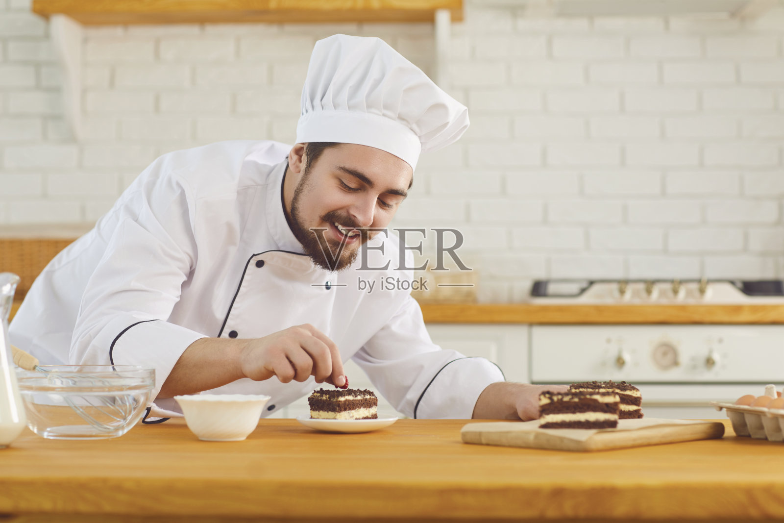 一位男糕点师正在厨房烘焙室装饰蛋糕照片摄影图片