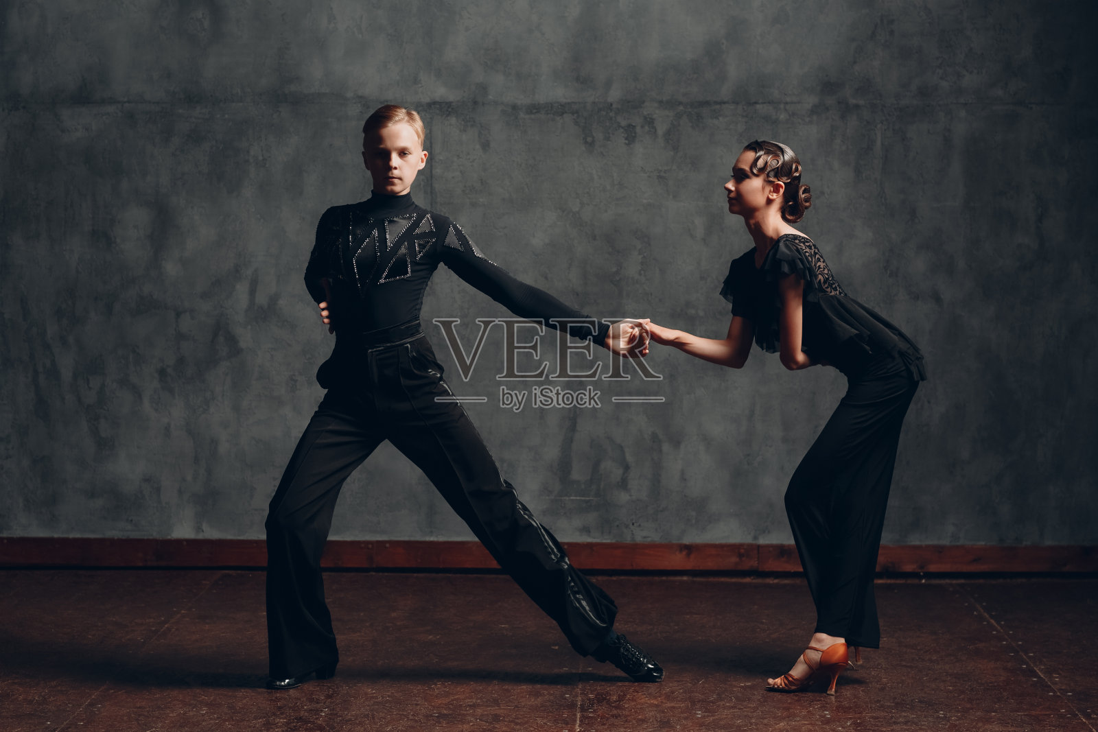 一对穿着黑色礼服的年轻男女在舞厅跳伦巴舞。照片摄影图片
