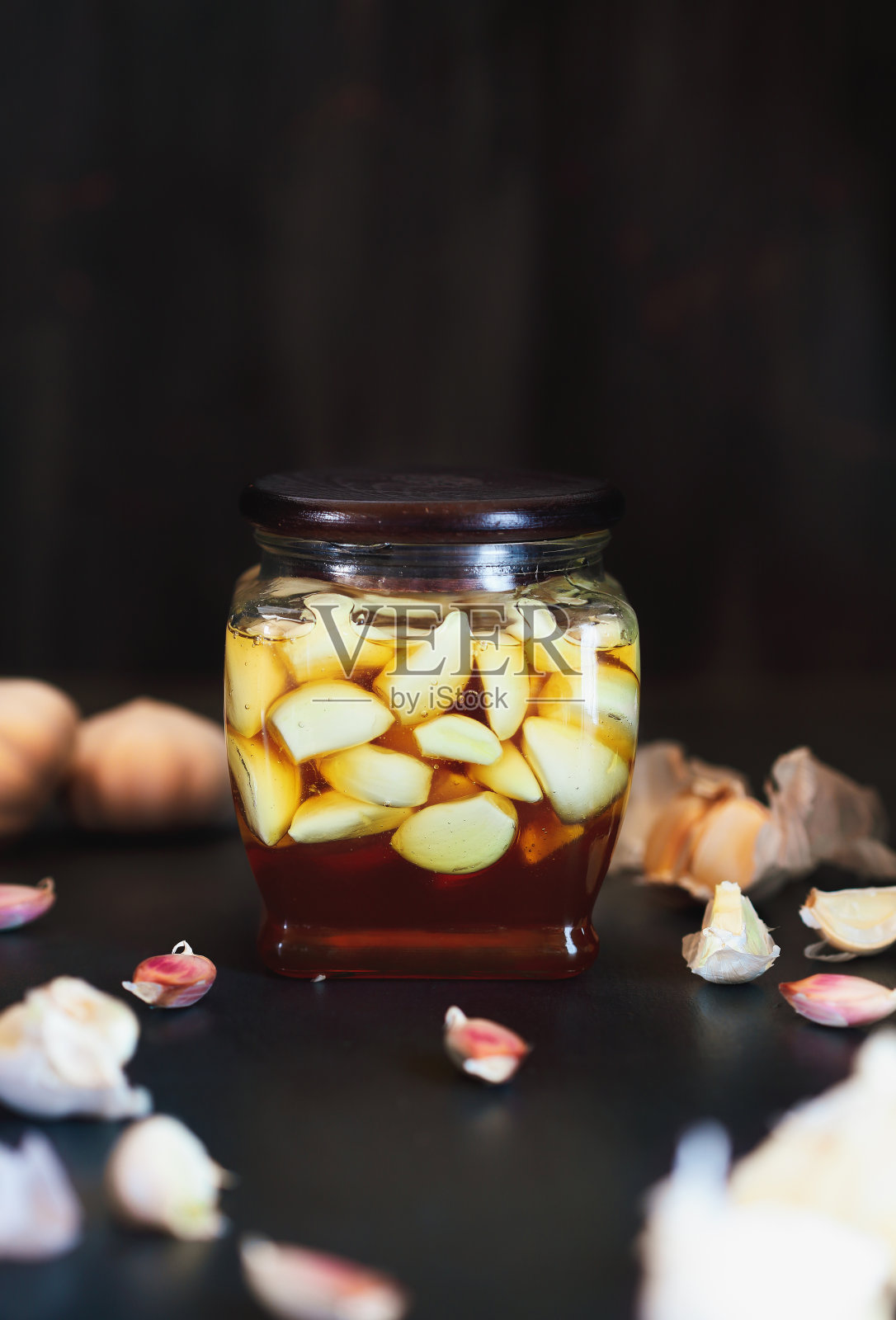 发酵的蒜瓣放在一罐蜂蜜里，蜂蜜是益生菌的丰富来源，背景是质朴的木头照片摄影图片