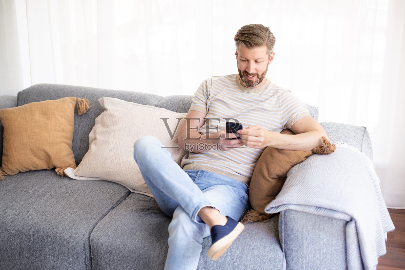 一个男人在家里的沙发上放松地玩着手机照片摄影图片