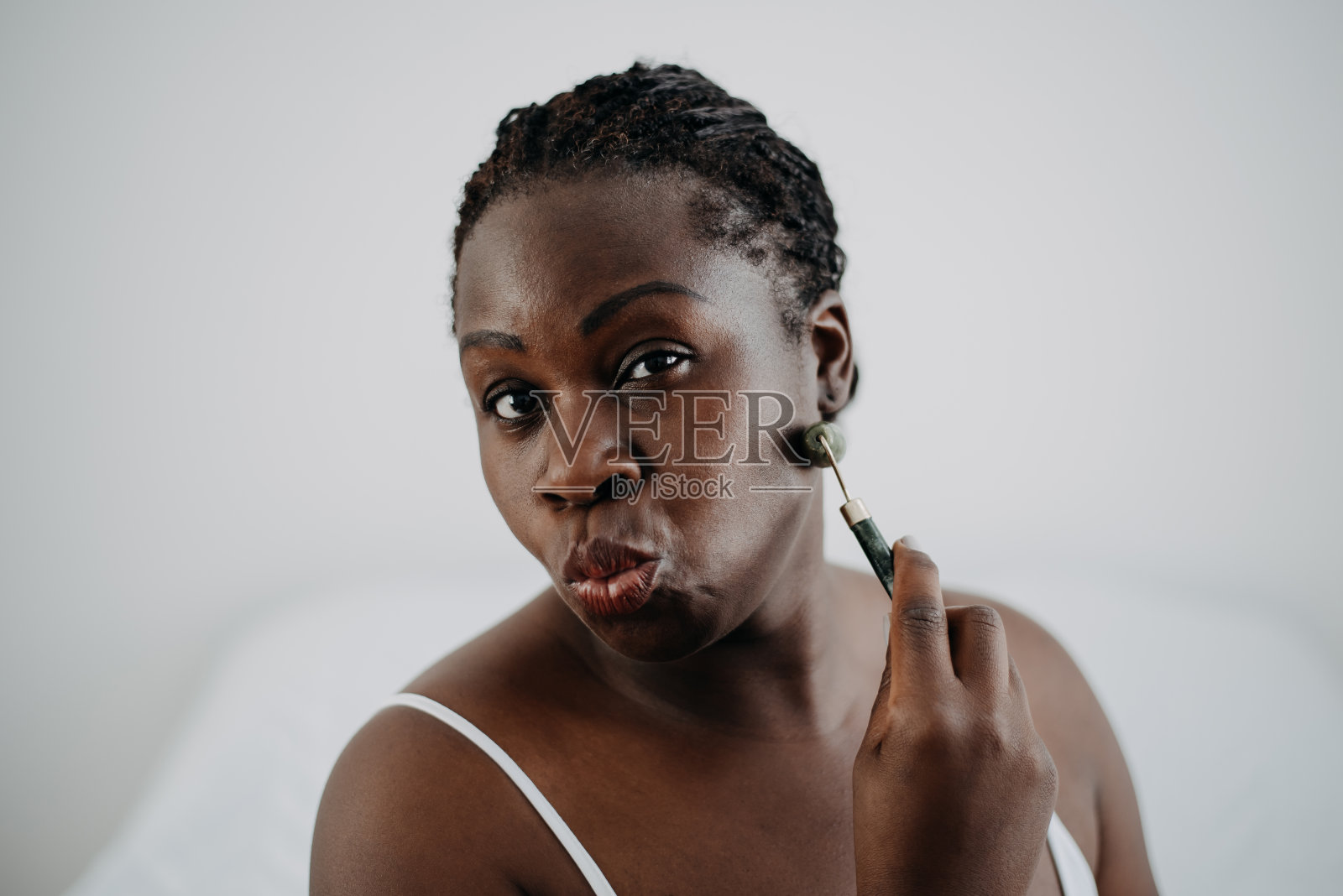 皮肤护理黑人妇女使用玉面部滚轮照片摄影图片
