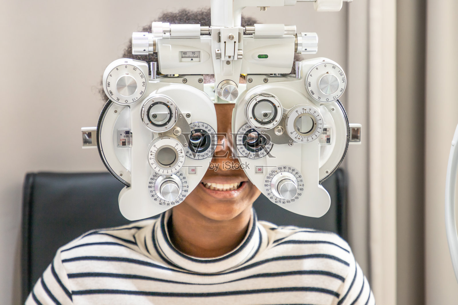 非洲年轻女子女孩在诊所或眼镜店做眼睛检查，坐在摄影器材前。护眼的概念。照片摄影图片
