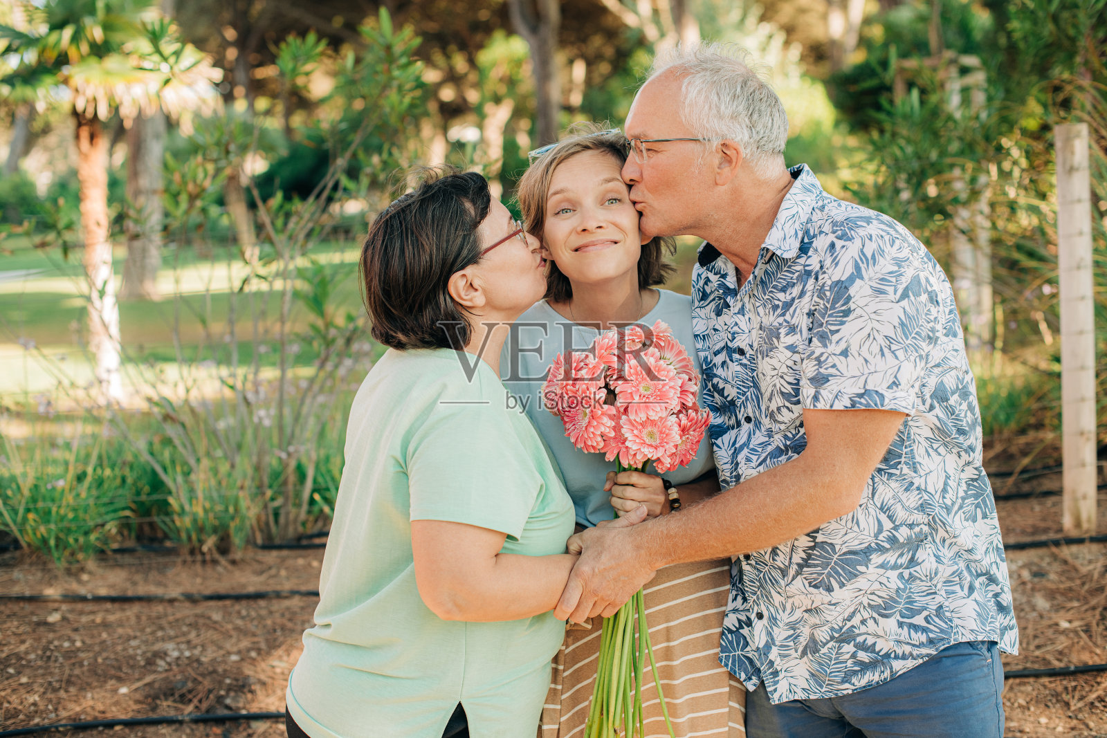 幸福的父母在亲吻他们的成年女儿照片摄影图片