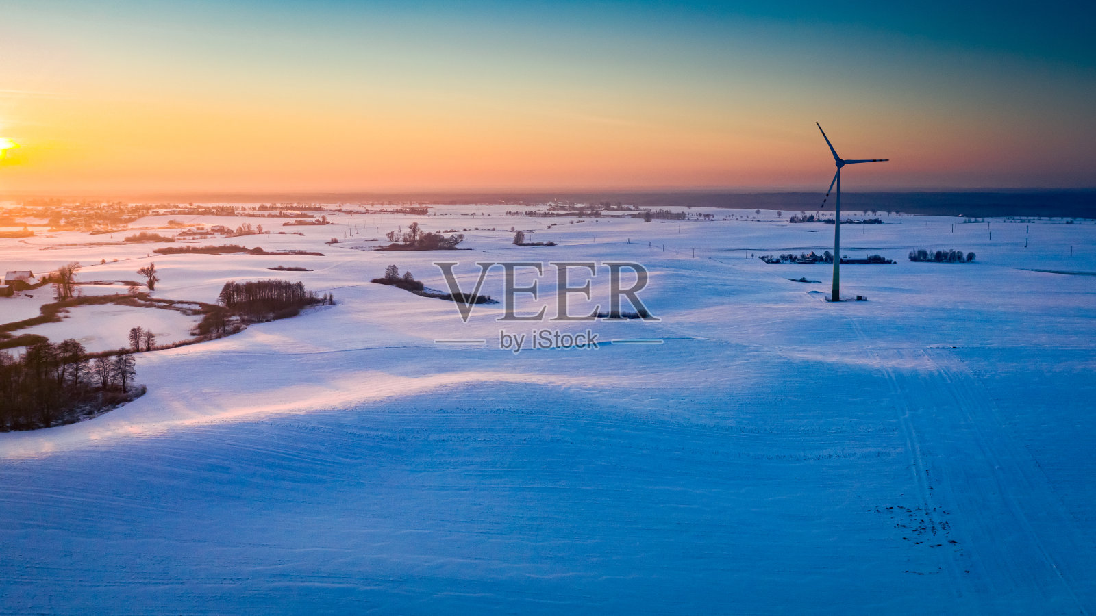 日出时雪域上的风力发电机。替代能源,冬天。照片摄影图片