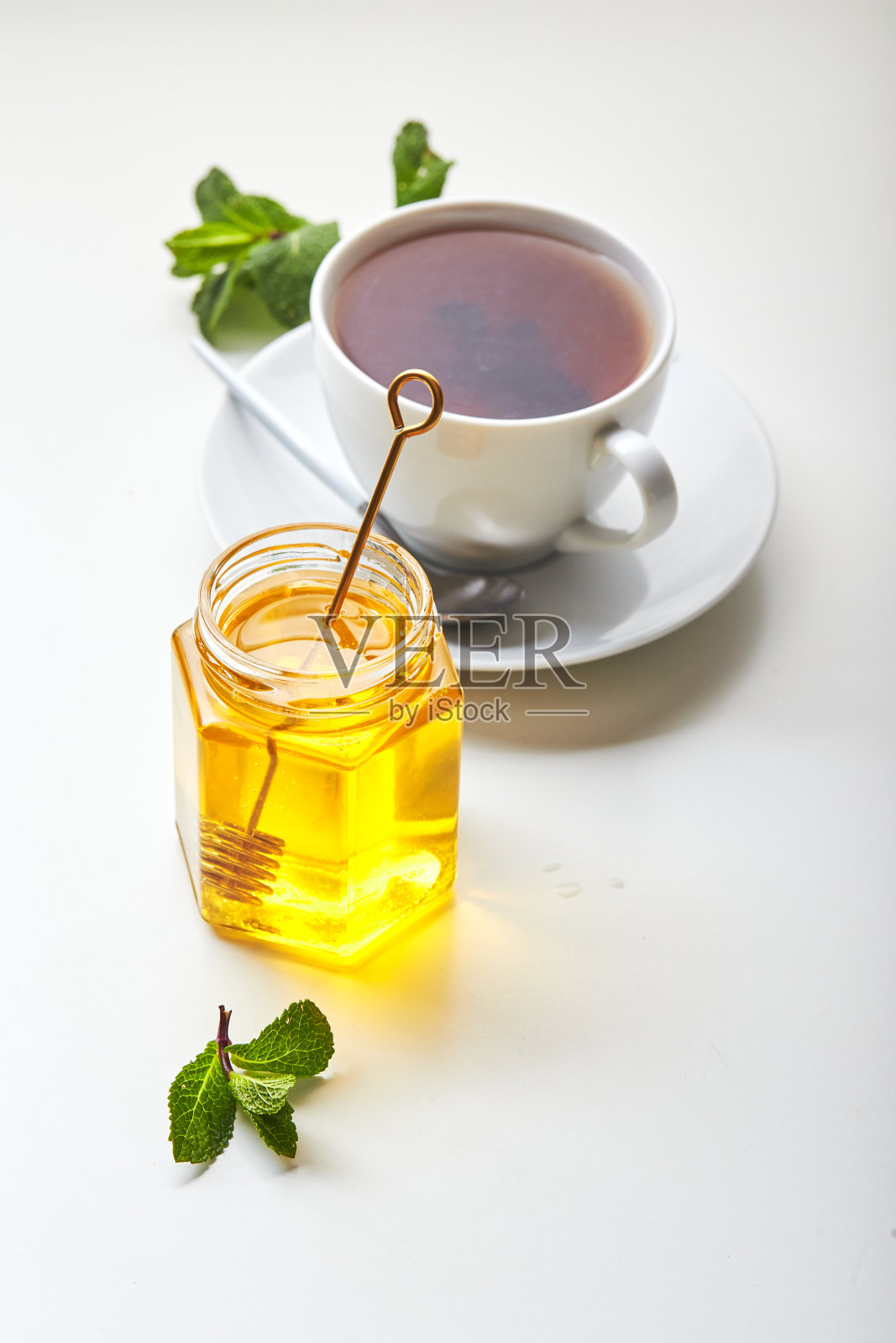 白杯红茶，加入薄荷叶和蜂蜜。镇静和恢复活力的茶，抗压力和放松照片摄影图片