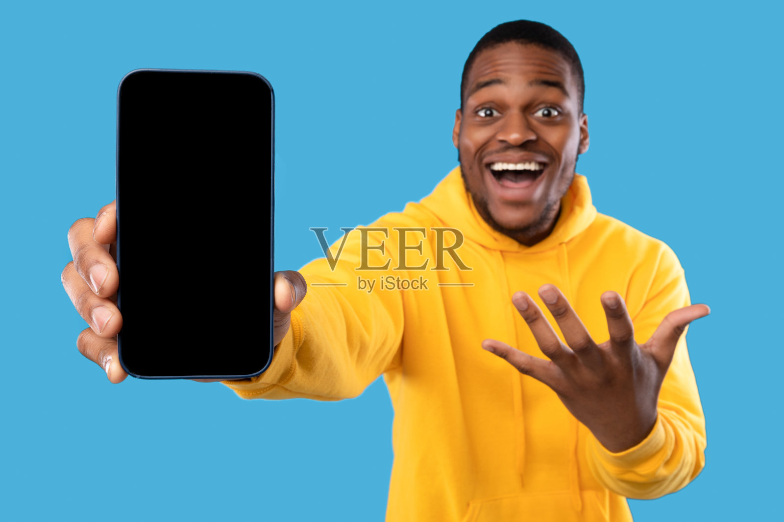 激动的非洲裔美国人在蓝色背景上显示手机屏幕照片摄影图片