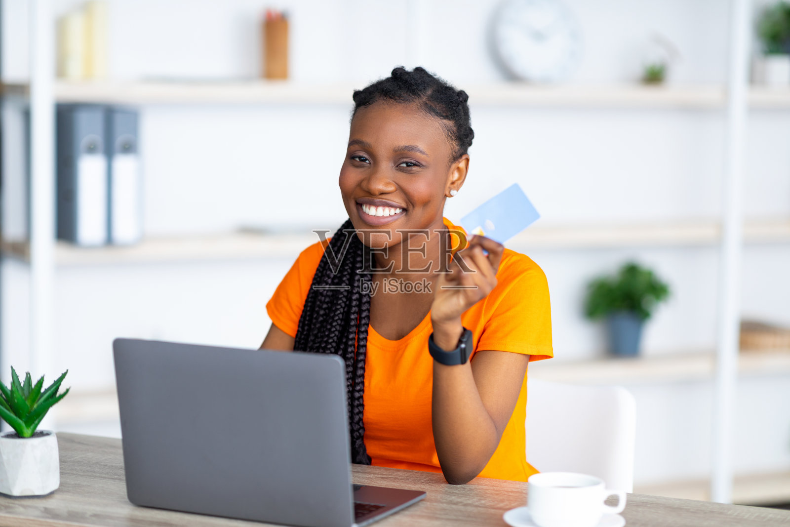 开朗的非洲裔美国女士使用笔记本电脑和信用卡，在网上购物，在家远程购物照片摄影图片