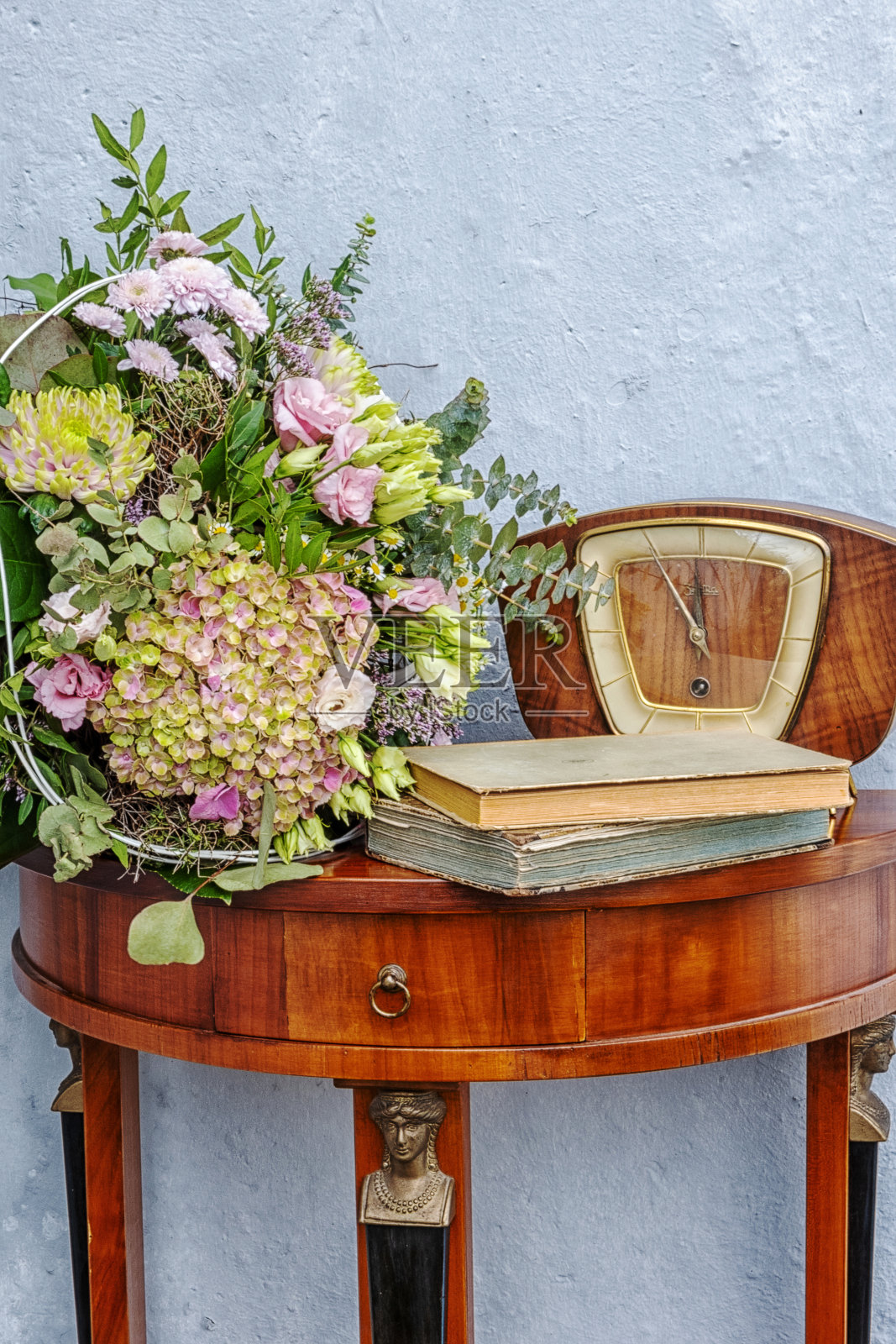 有花、旧钟和书的古董餐具柜照片摄影图片