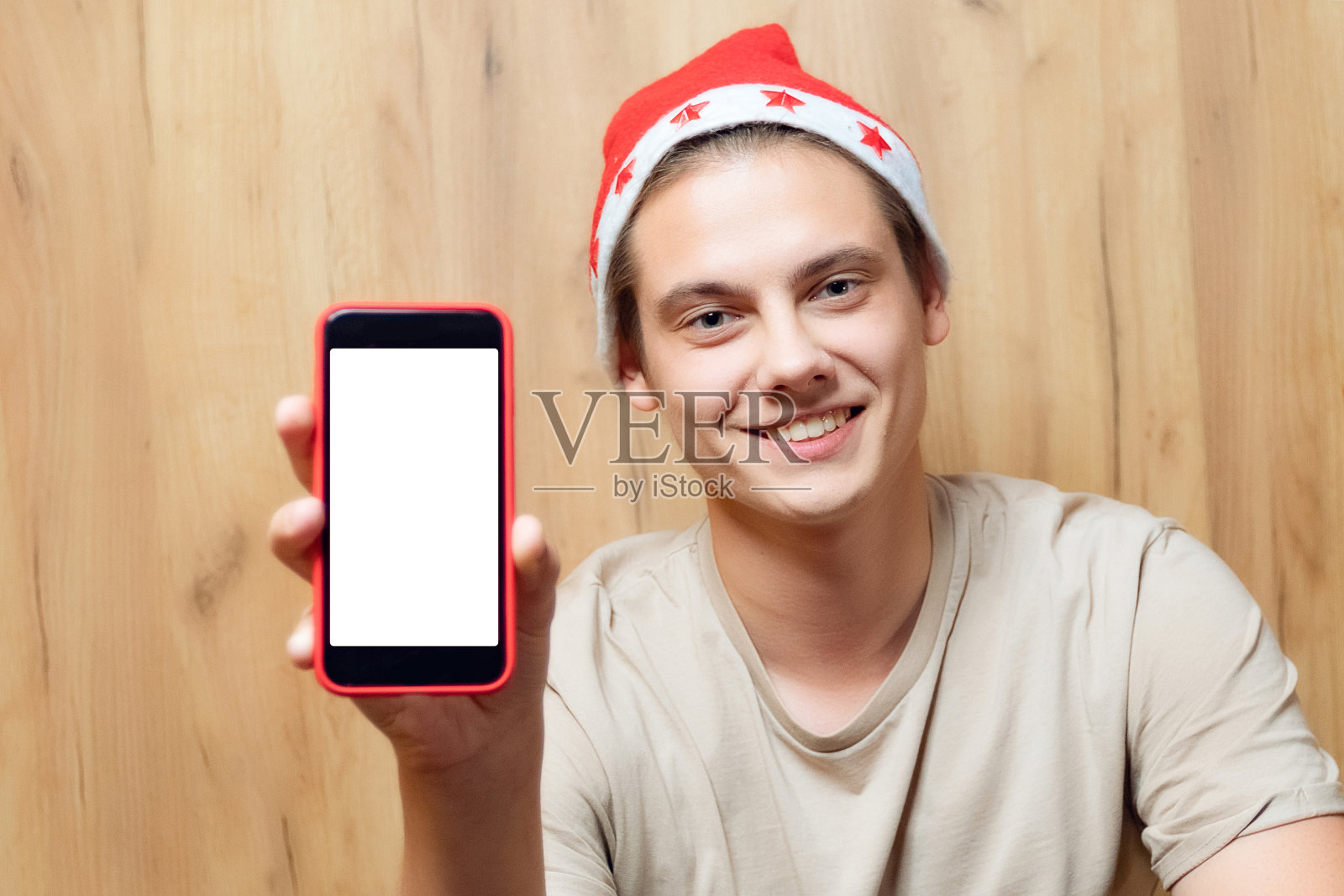 一名戴着圣诞老人帽子的男子正在使用手机。人手持智能手机进行视频通话和交流，应用概念与空白屏幕为模板和复制空间照片摄影图片