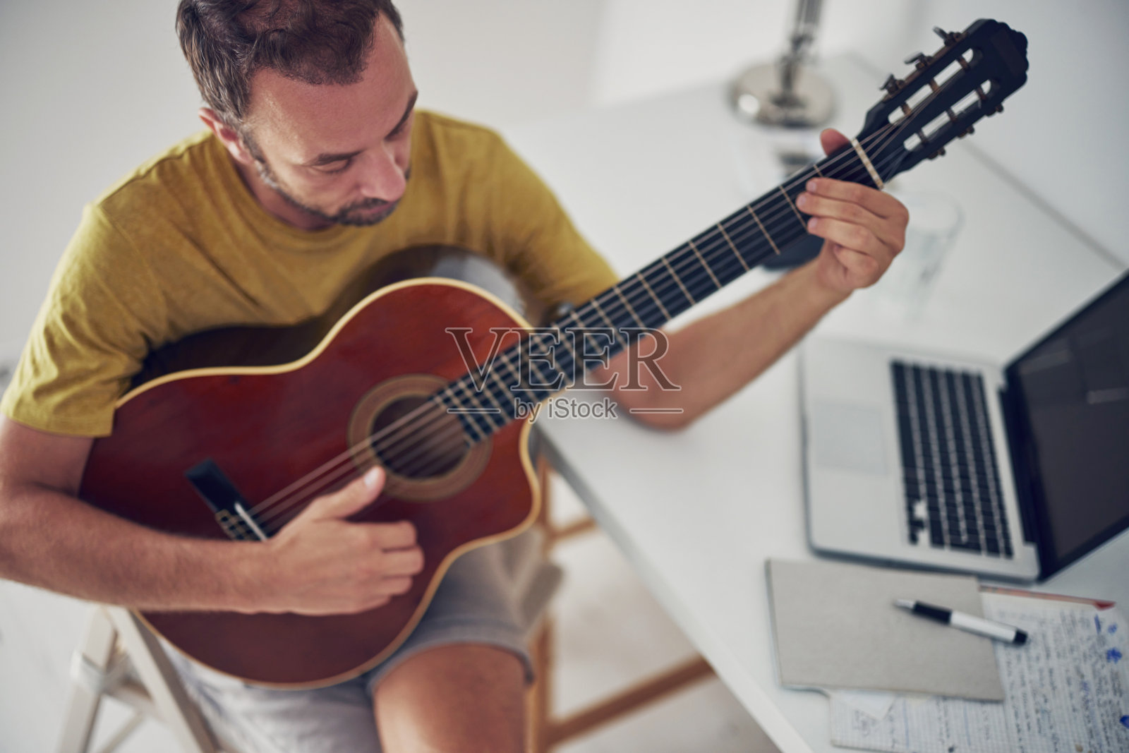 男人在家里弹吉他。照片摄影图片