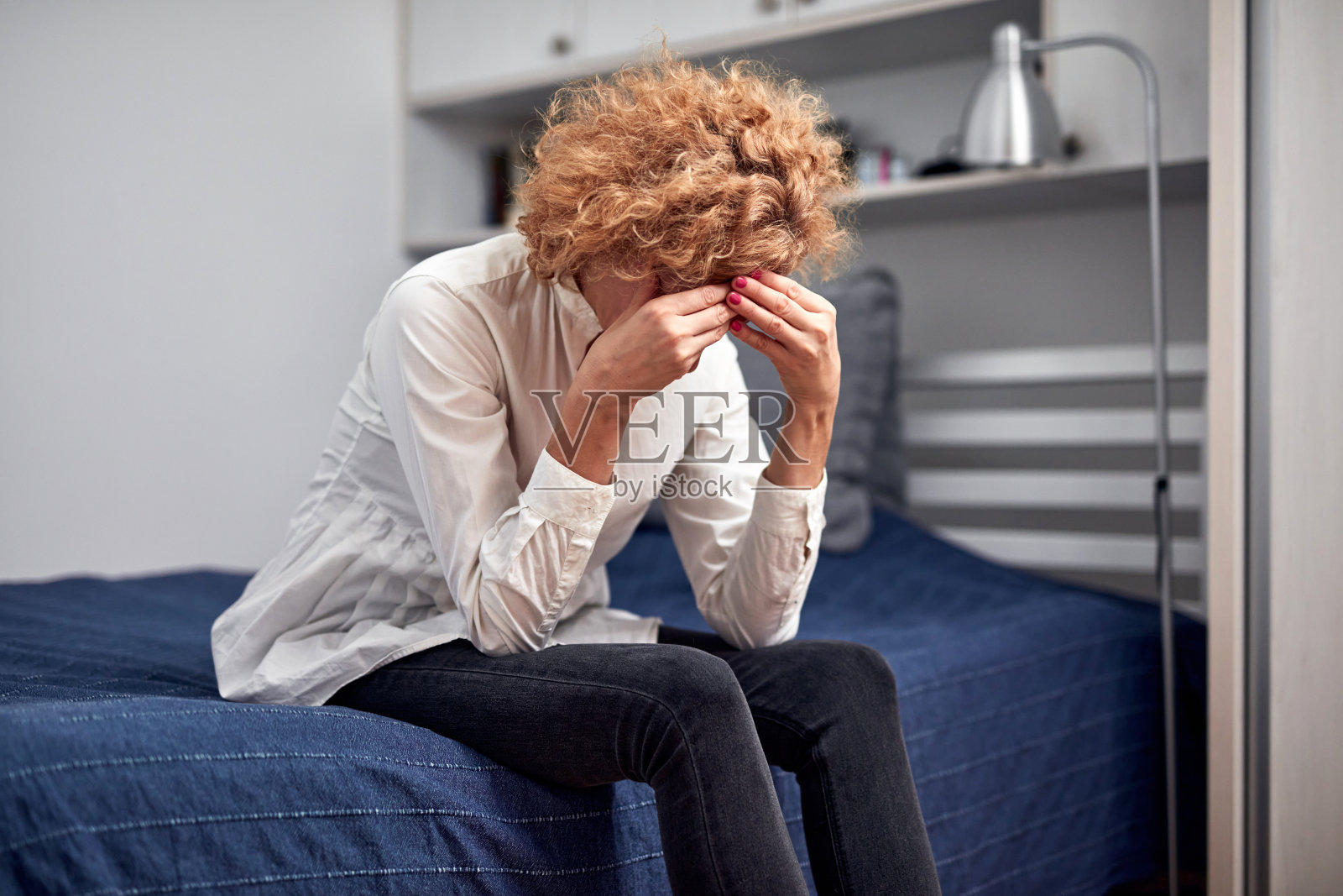 头痛、宿醉、精神和抑郁的女人坐在家里的床上。照片摄影图片