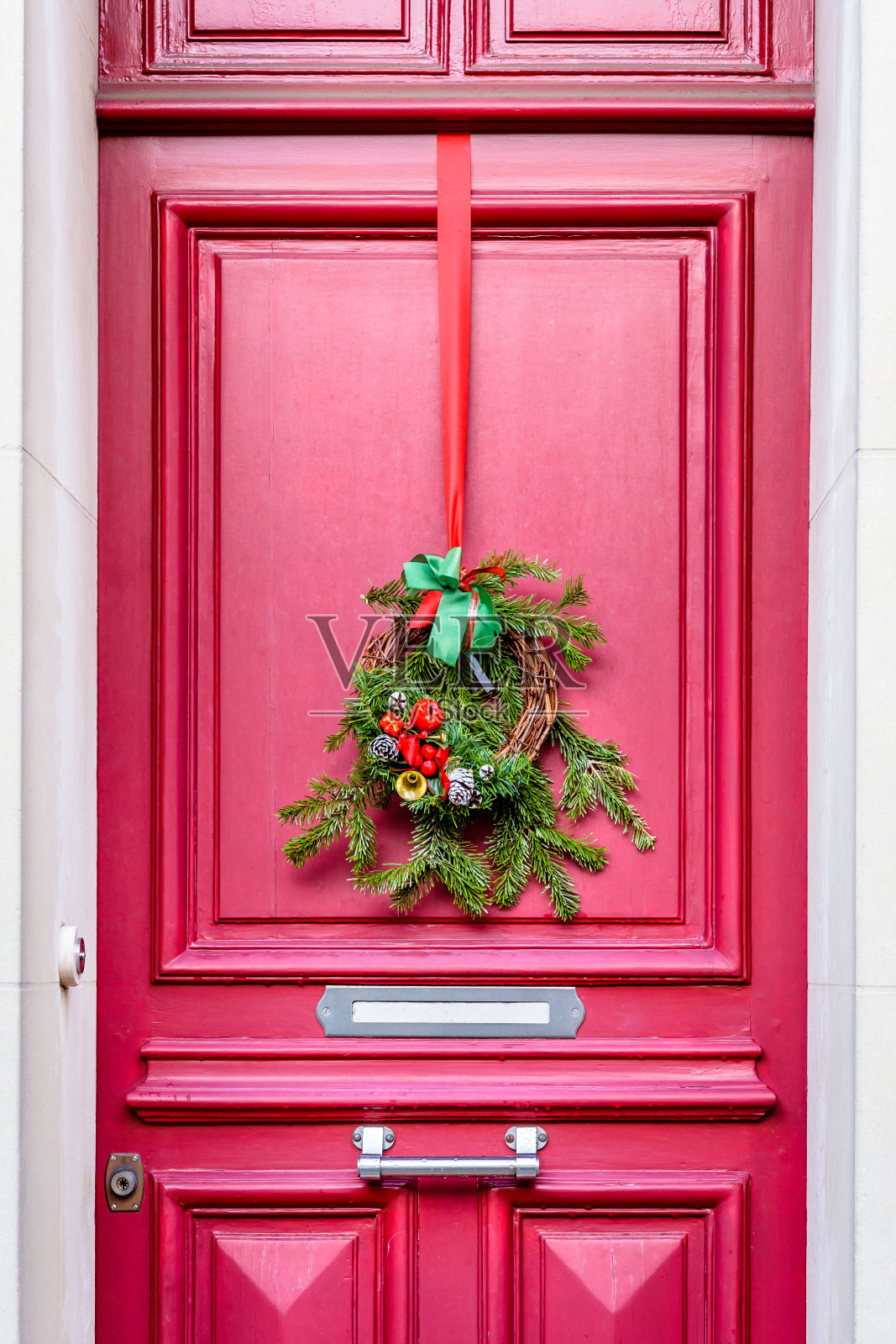挂在红色大门上的圣诞花冠。照片摄影图片