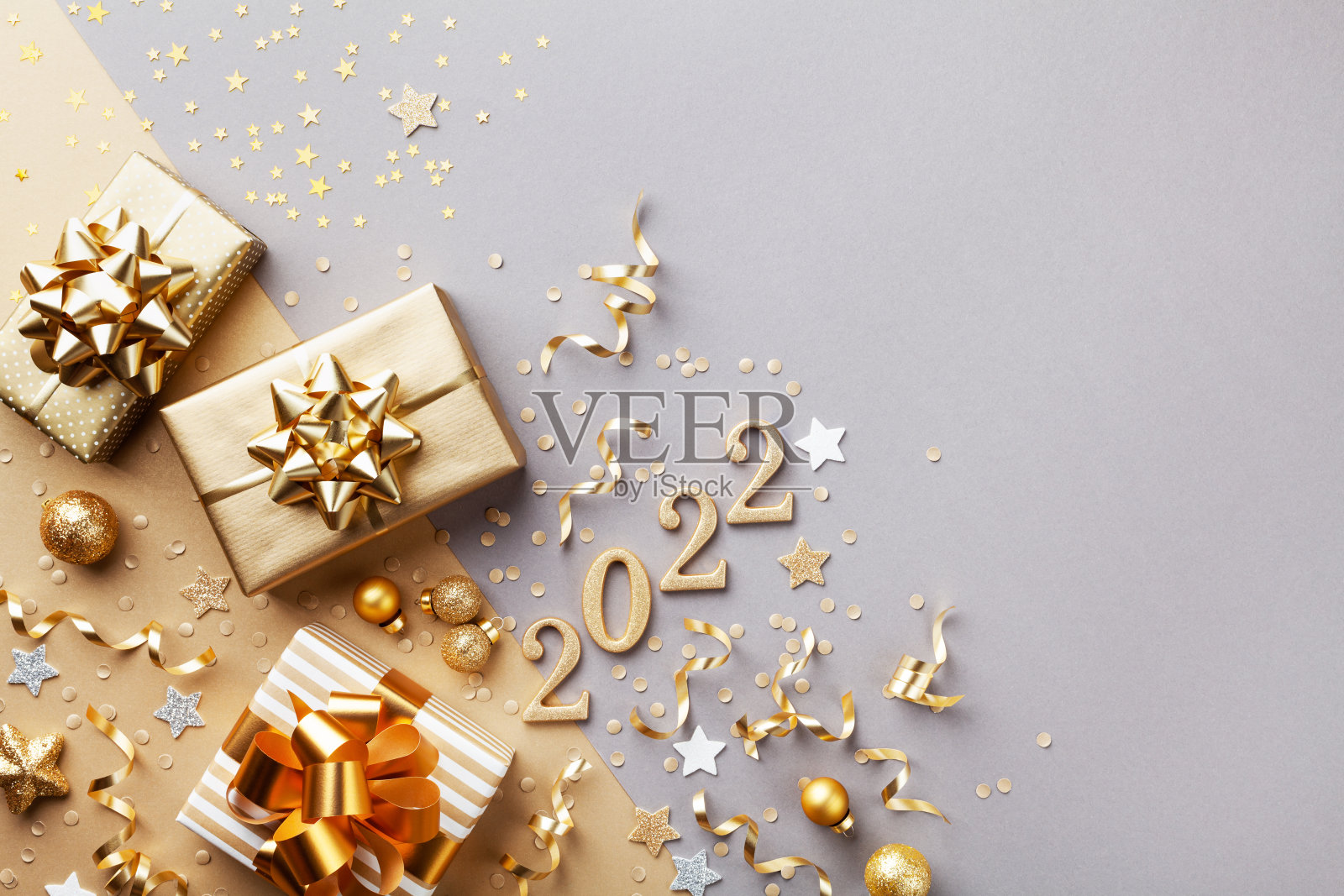 圣诞节和新年背景。带有金色蝴蝶结的金色礼物或礼物盒，2022号和彩色纸屑俯视图。照片摄影图片