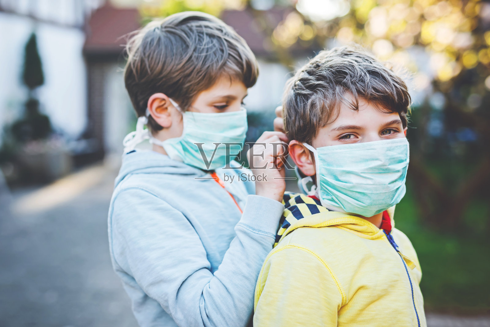 两个小男孩戴着医用口罩，以预防大流行性冠状病毒疾病。孩子们、可爱的兄弟姐妹和最好的朋友们使用防护装备抗击covid - 19。照片摄影图片
