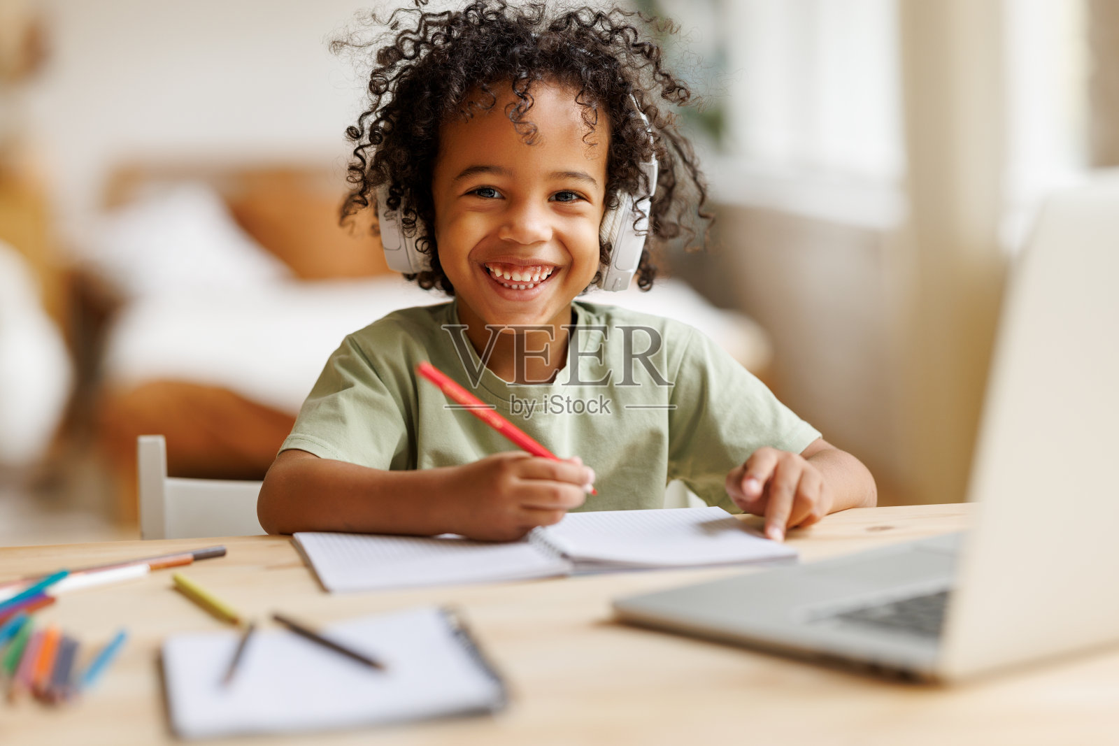 戴着耳机微笑的非洲裔美国学童在家用笔记本电脑在线学习照片摄影图片