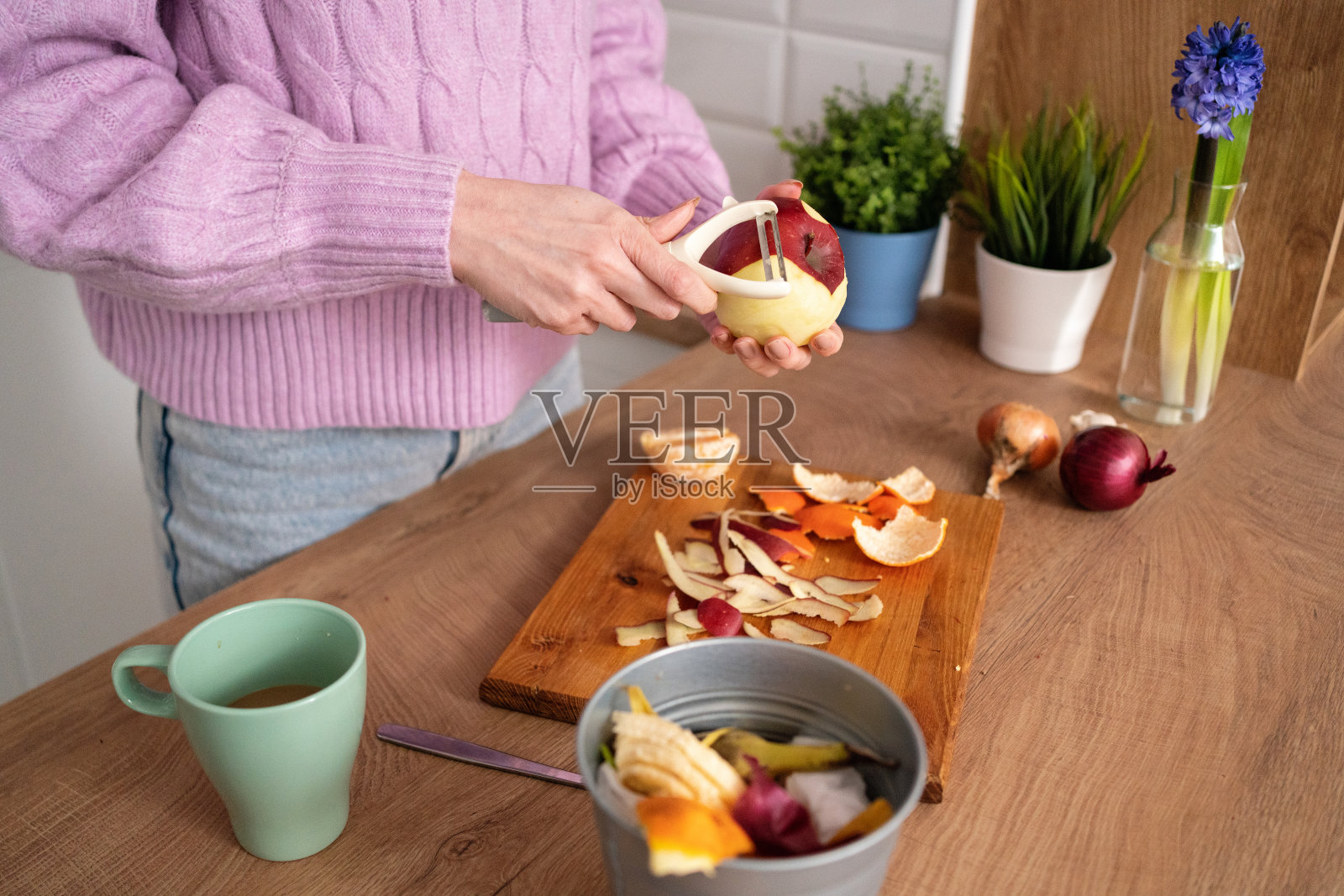 年轻女子在厨房用削皮器削苹果照片摄影图片_ID:414201166-Veer图库