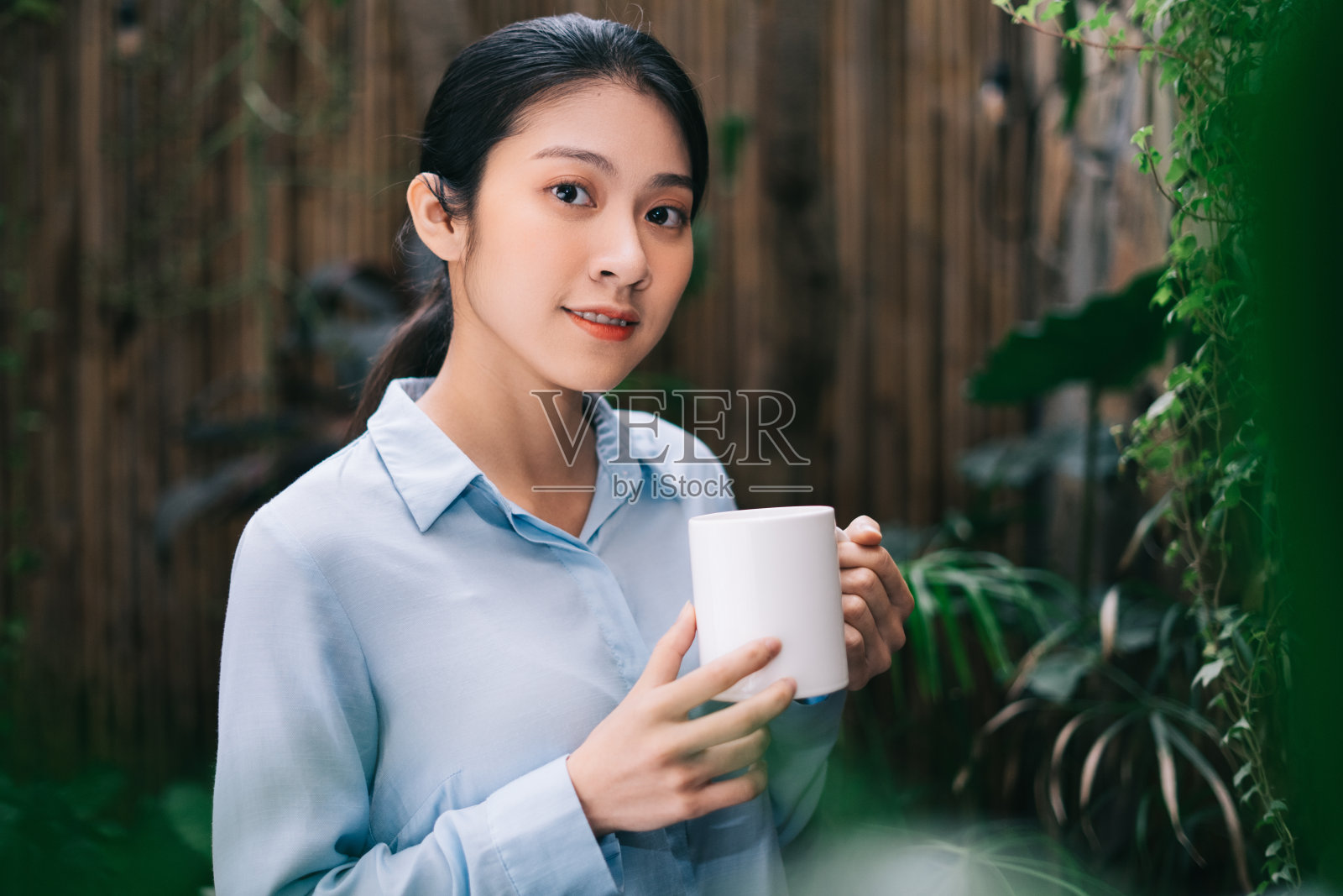 美丽的年轻亚洲女人放松在花园和喝茶照片摄影图片