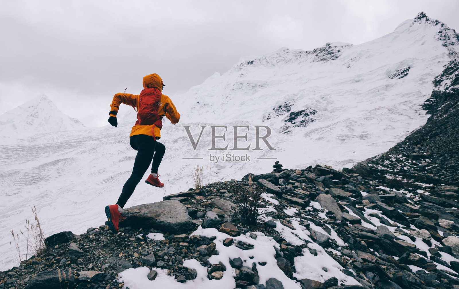 女子越野跑者跑到冬季雪山的山顶照片摄影图片