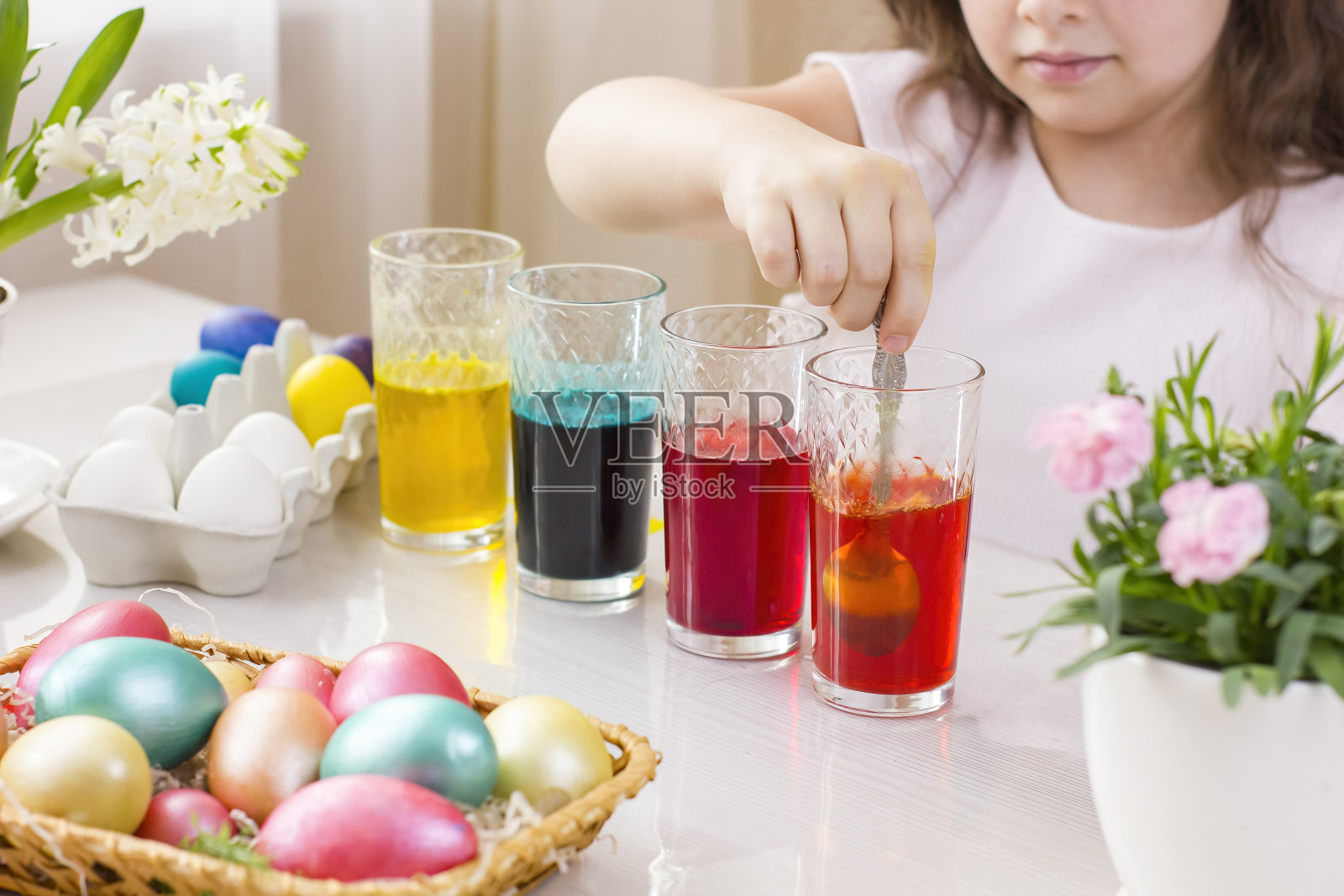 可爱的小女孩用液体染料在杯子里画复活节彩蛋。照片摄影图片