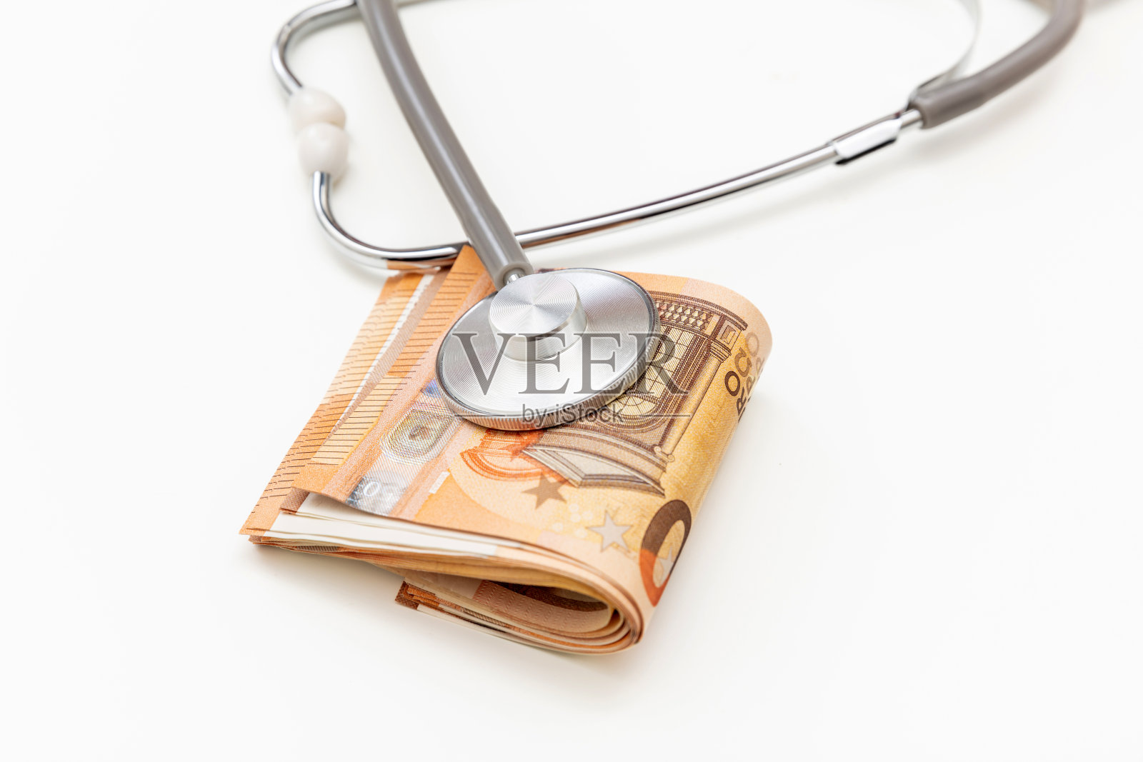 医疗保健成本。医用听诊器在欧元钞票上孤立的堆叠上白色，关闭照片摄影图片