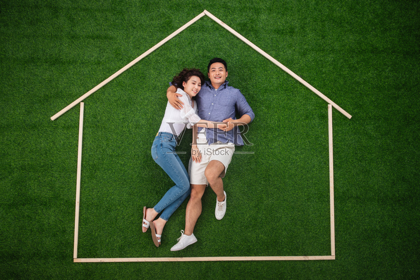青年伴侣躺在草地上的房子轮廓里照片摄影图片