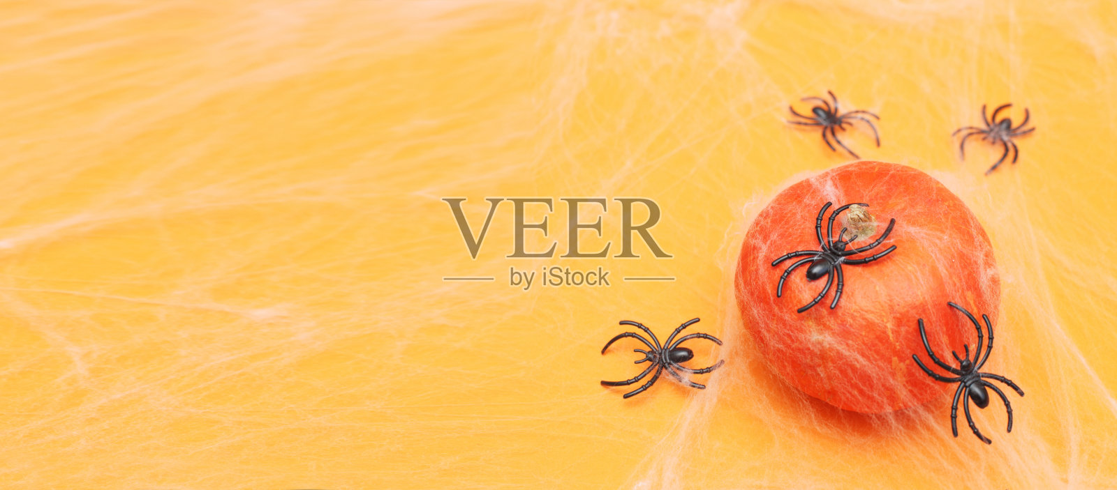 万圣节南瓜与蜘蛛网和黑色蜘蛛在橙色的背景。照片摄影图片