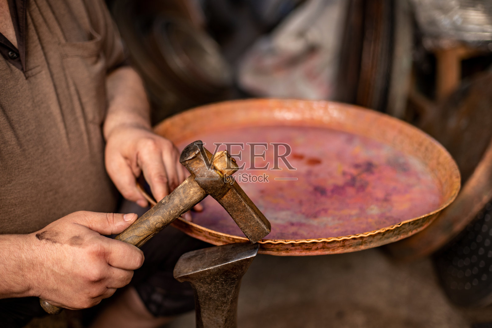 铜匠手工锻造铜金属。照片摄影图片