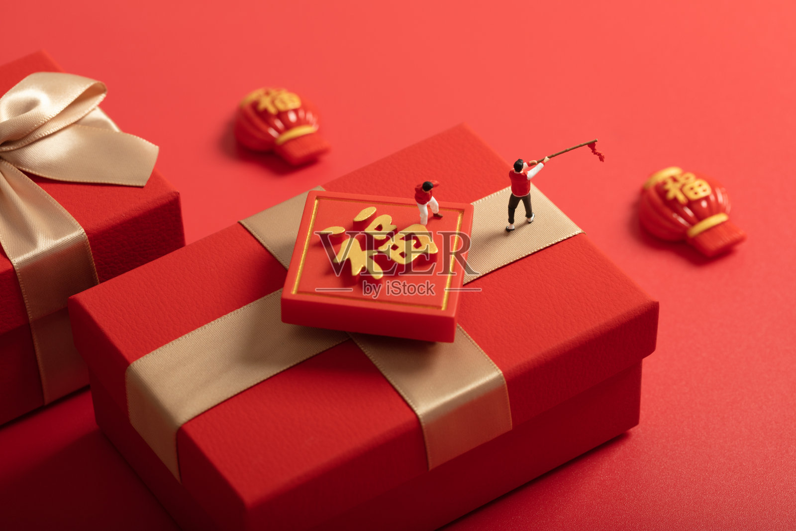 微缩创意春节在红色礼物盒上放鞭炮的父子照片摄影图片
