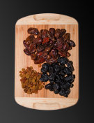 一把干枣、葡萄干和梅干放在厨房的木板上。干果的背景。健康食品的概念。在黑色背景上隔离。摄影图片